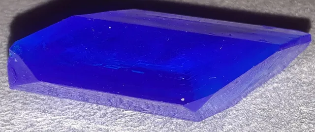 Un monocristal de sulfato de cobre, el azul intenso del laboratorio. Aquí la red es otra y la forma también: una especie de rombo con las caras planas.
